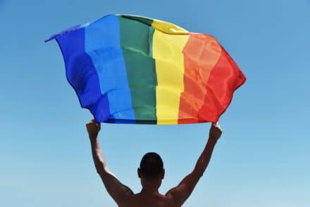 man with a rainbow flag over his head